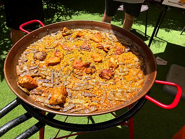 Finished paella valenciana with chicken and ferraura beans in a pan with red handles